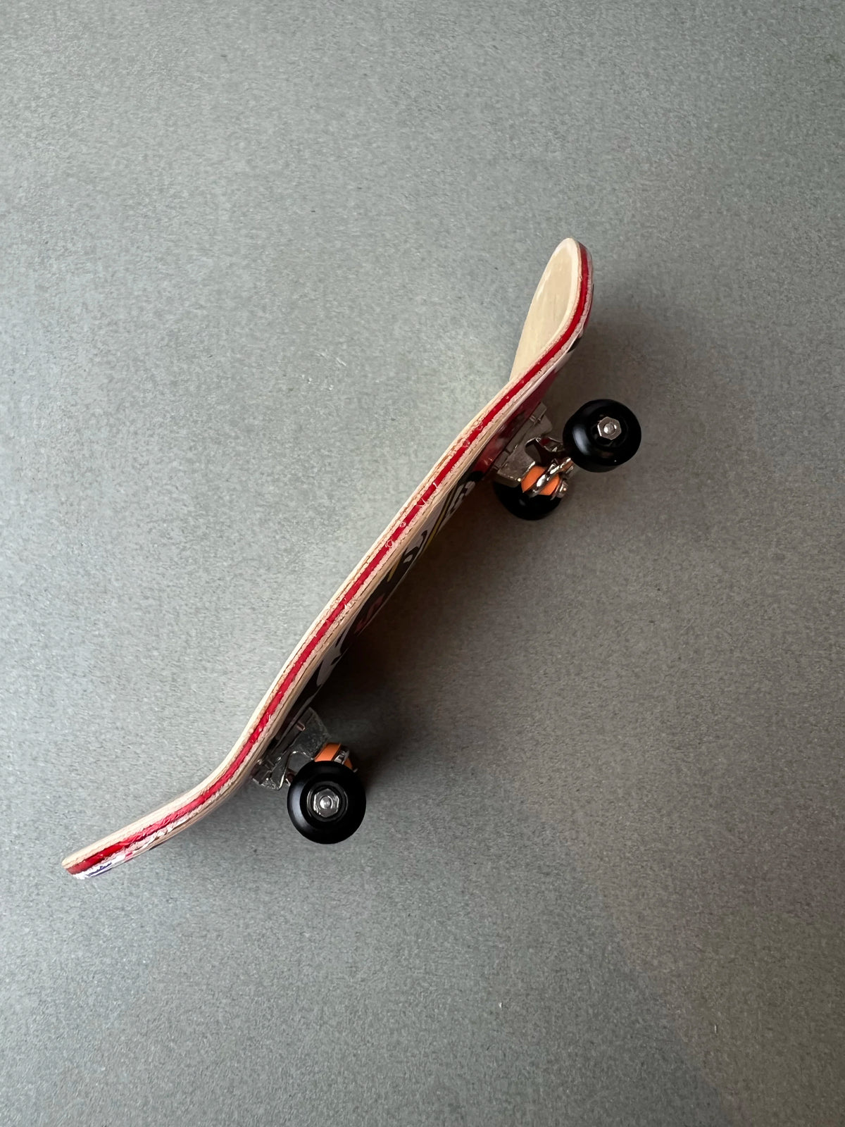 Death Gold de Finger3flip, fingerboard Pro de 34 mm de perfil, con la concavidad de la tabla y los ejes a la vista