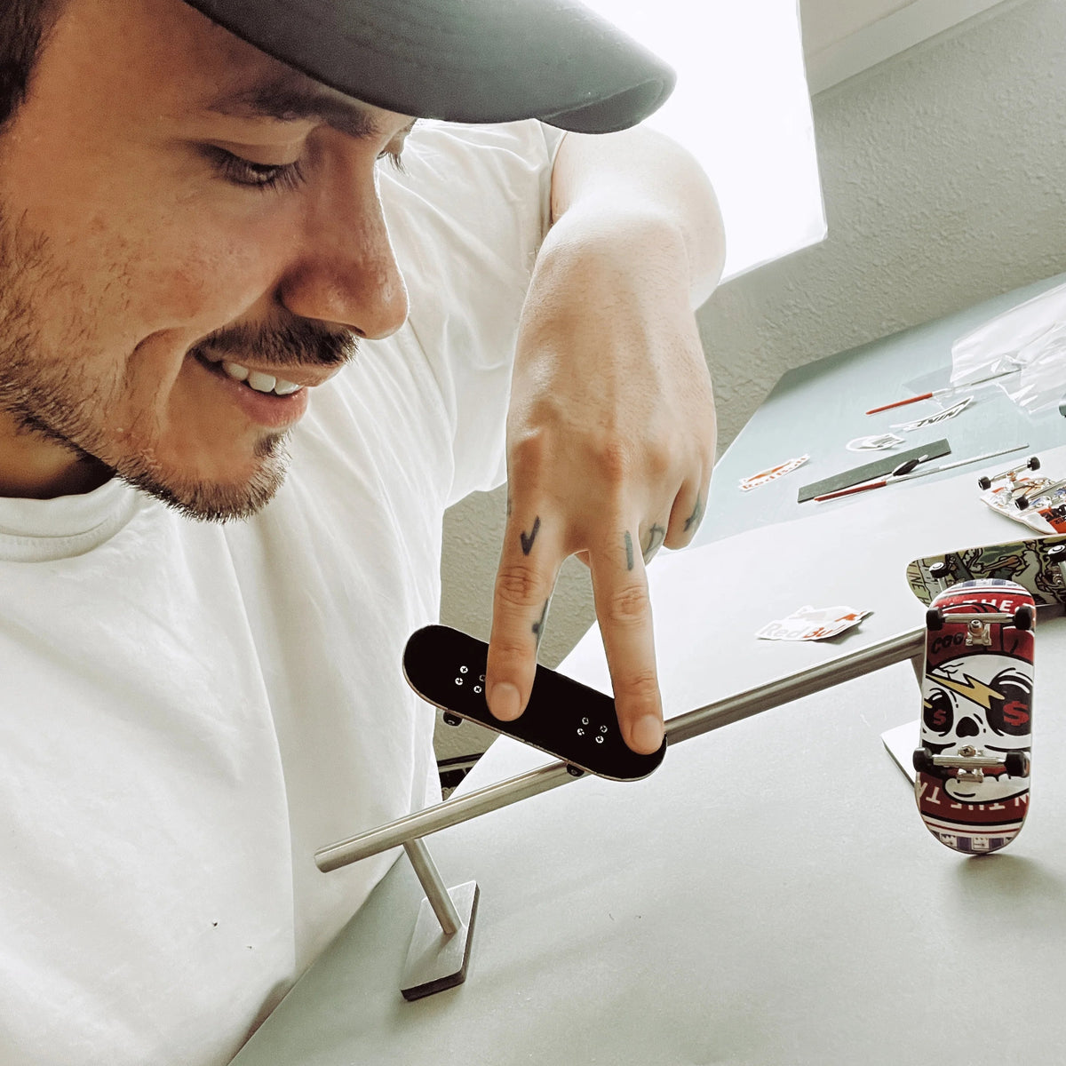 Antony probando un truco con un fingerboard sobre un rail en su mesa de trabajo